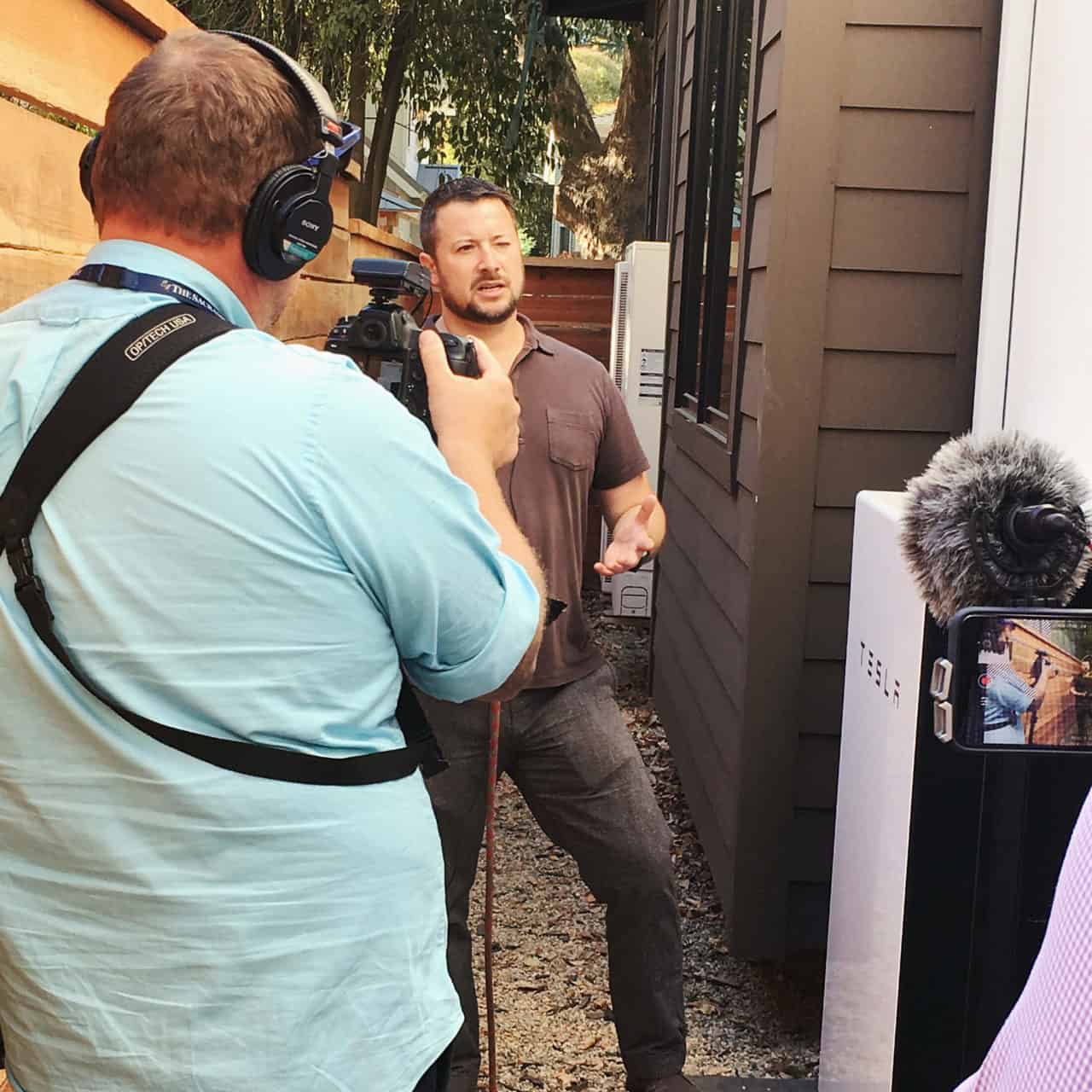 Joaquin Rangel and reporters check out eco-home's Tesla power walls. 